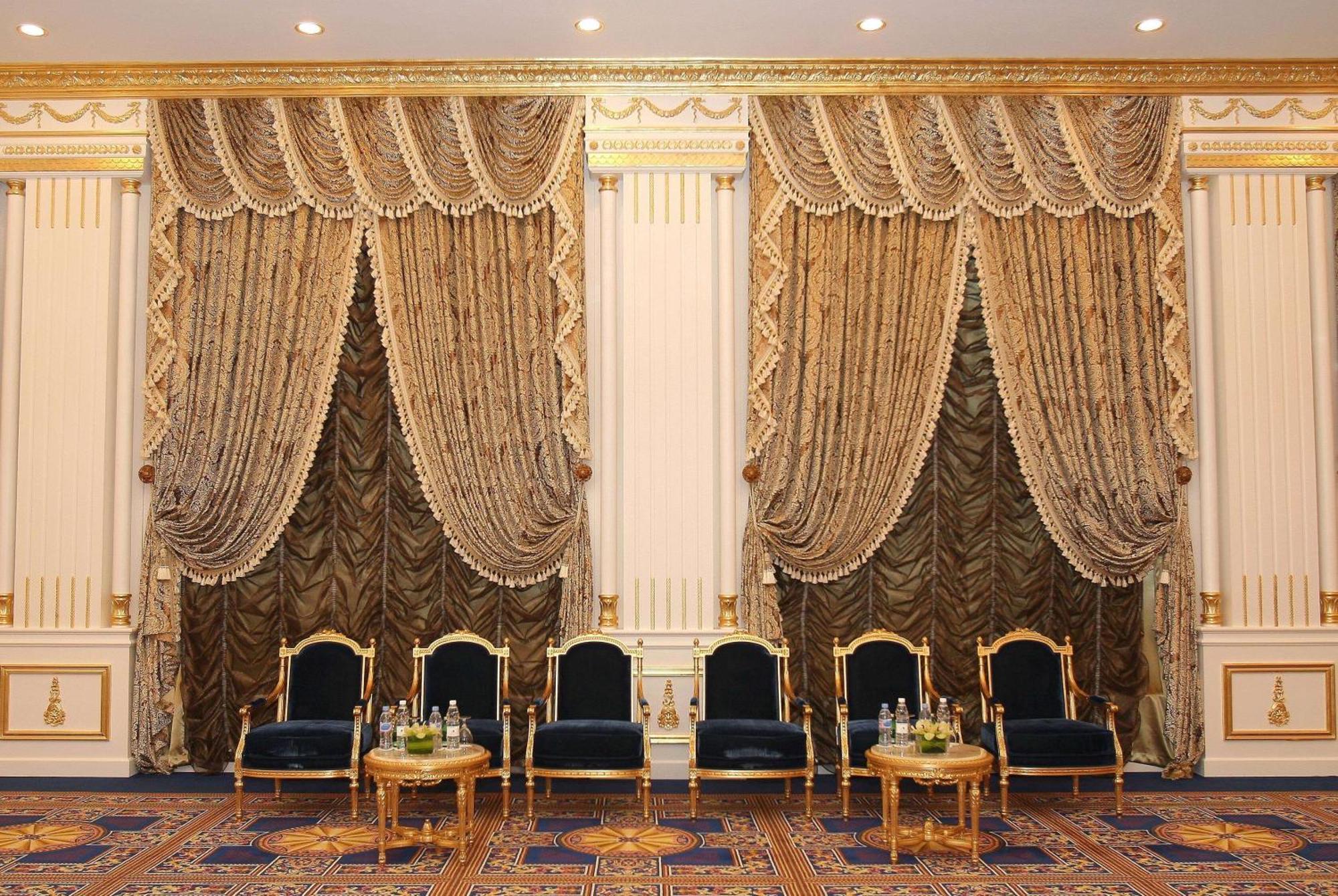 Grand Regency Doha, Trademark Collection By Wyndham Exterior photo The photo shows an elegantly decorated interior space. There are two sets of opulent curtains on the walls, featuring rich fabrics with ornate designs and gold accents. The curtains are paired with decorative tiebacks. In front of the curtains, there